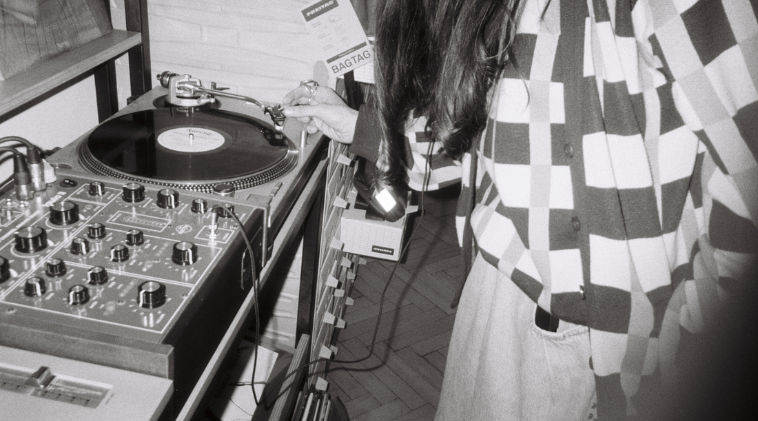 A woman in a record store standing over a turntable
