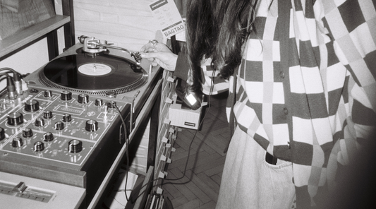 A woman in a record store standing over a turntable